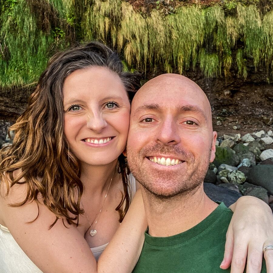 A man and woman smile at the camera. The women has her arm around the man.