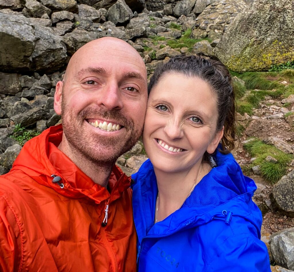 Close up picture of a couple, wearing orange and blue waterproof coats.