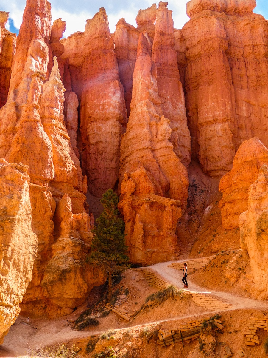 A woman stares up at the magnitude of the towering red hoodoos and rock formations above her in Bryce Canyon National Park.