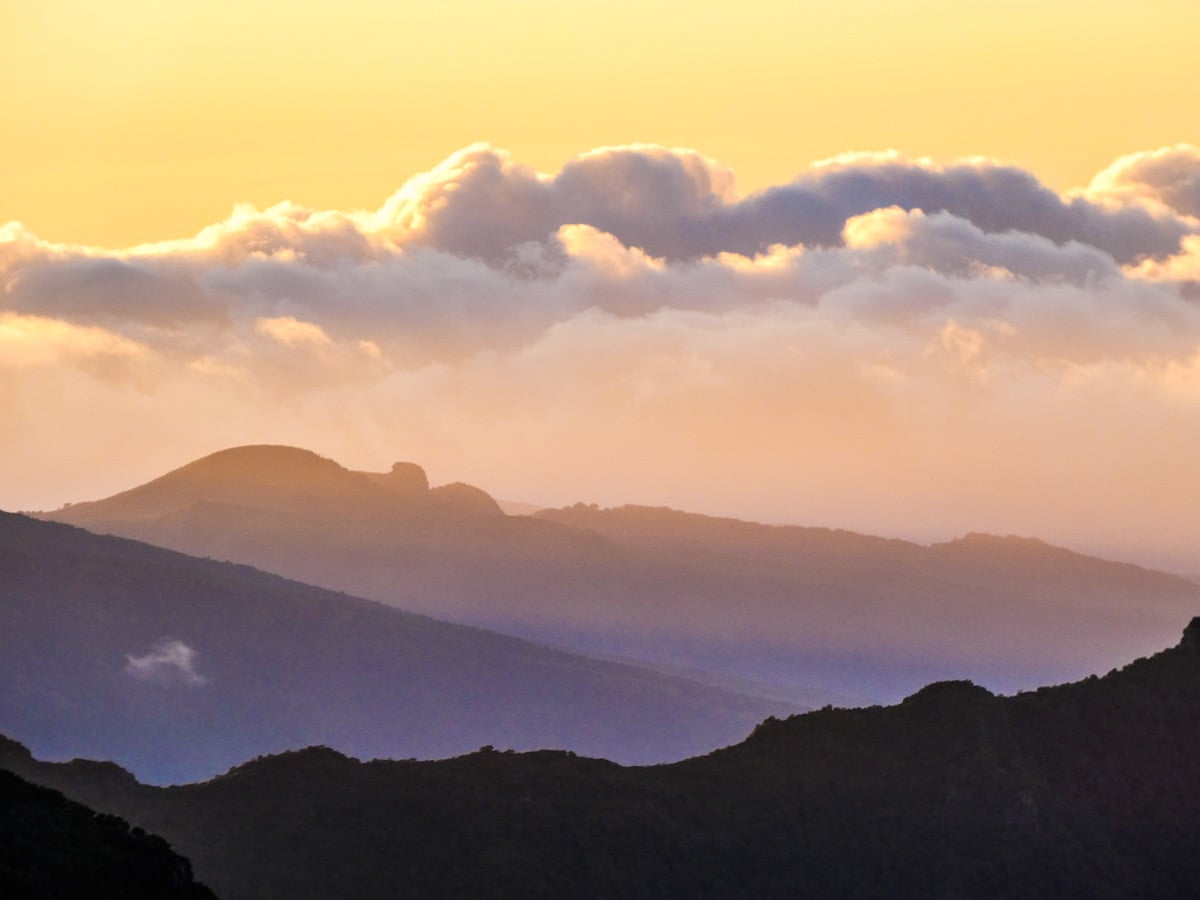 A beautiful sunset silhouettes the  black mountains in the distance with hues of purple.