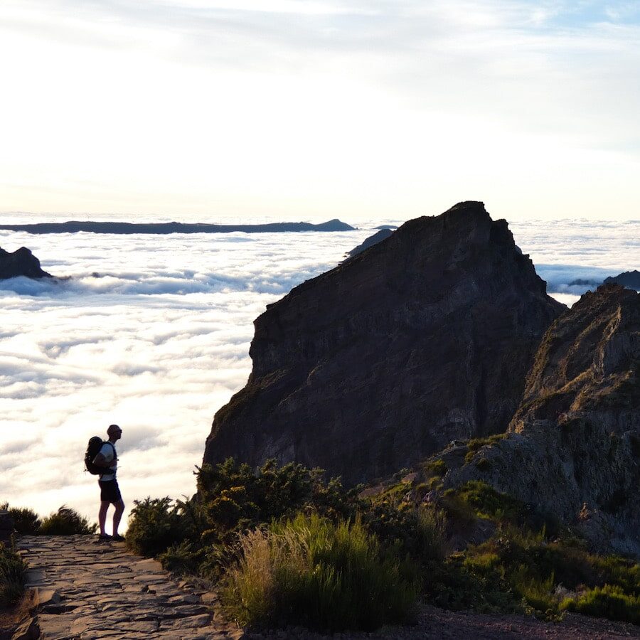 A silhouette of a man standing on a path above the clouds in Madeira.