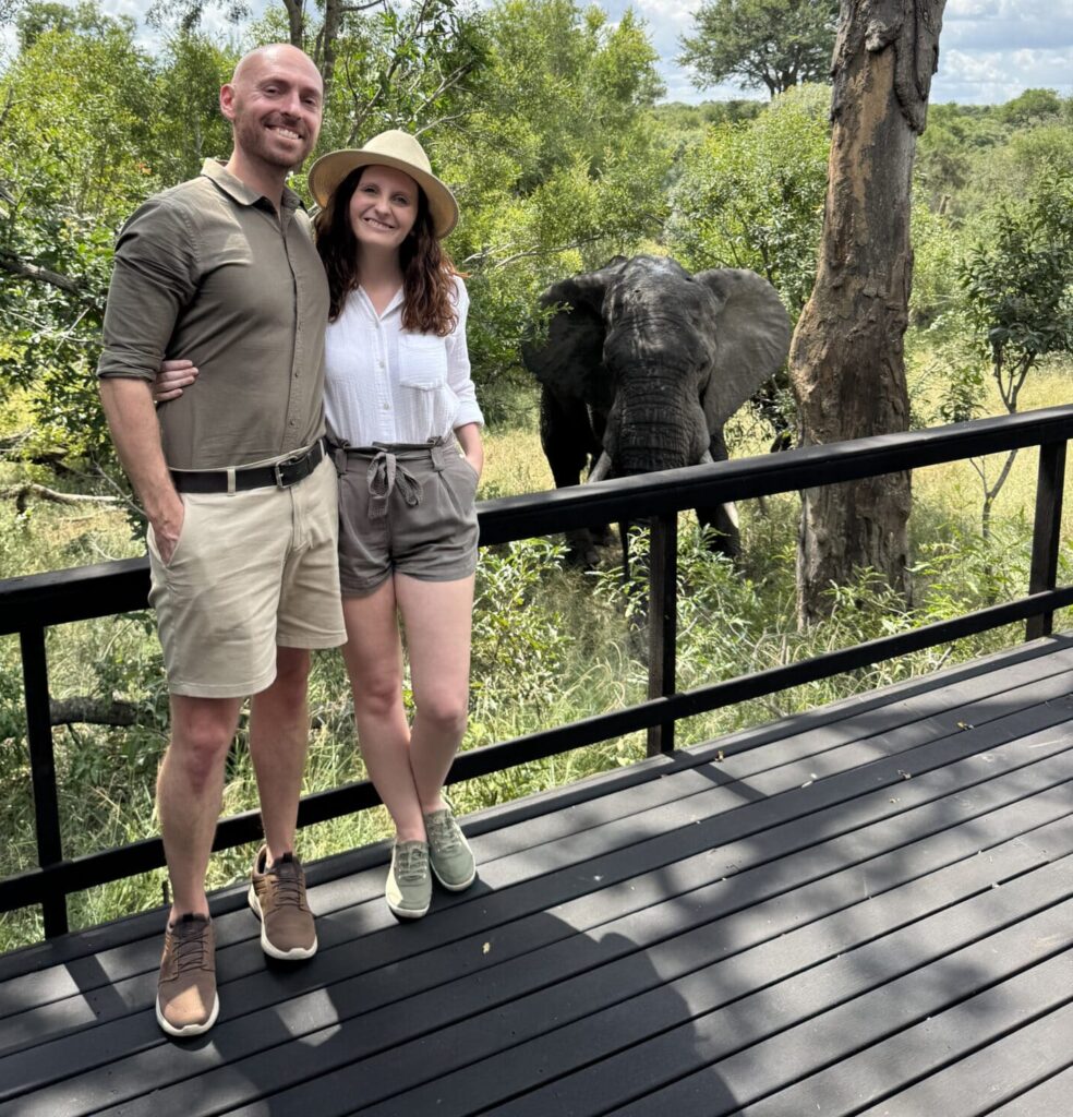 Liz and Leon from Mr and Mrs D Adventures in their luxury safari lodge with an elephant in the background in South Africa