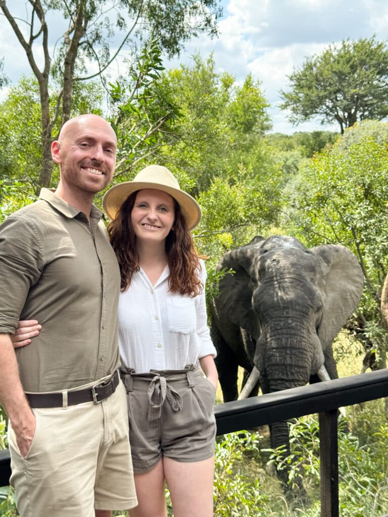 Liz and Leon from Mr and Mrs D Adventures on their lodge balcony with a elephant in bush in South Africa